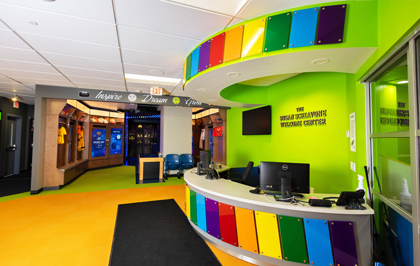 Interior view of the reception desk at the Zone with rainbow colored acrylic standoffs and lime green painted walls