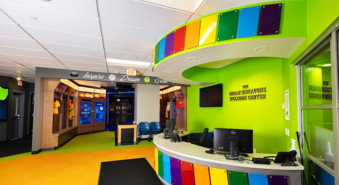 Interior view of the reception desk at the Zone with rainbow colored acrylic standoffs and lime green painted walls