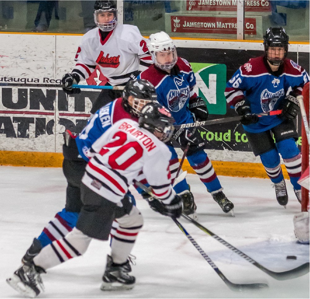 Youth hockey players on the Jamestown Lakers challenge the rival team for control of the puck